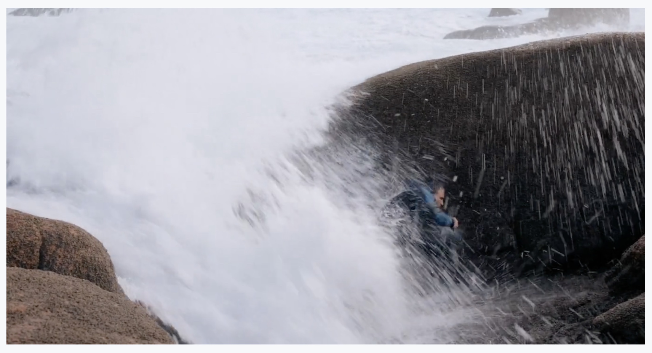 A barnacle hunter surrounded by waves between rocks